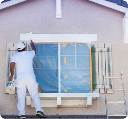 Painter applying fresh white trim paint around window