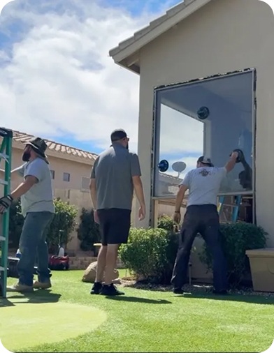 Team installing large glass window on residential home